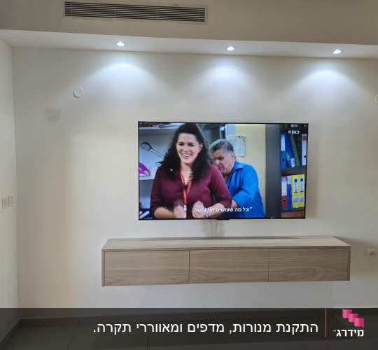 טלוויזיה מותקנת על קיר עם ארונית מתחת